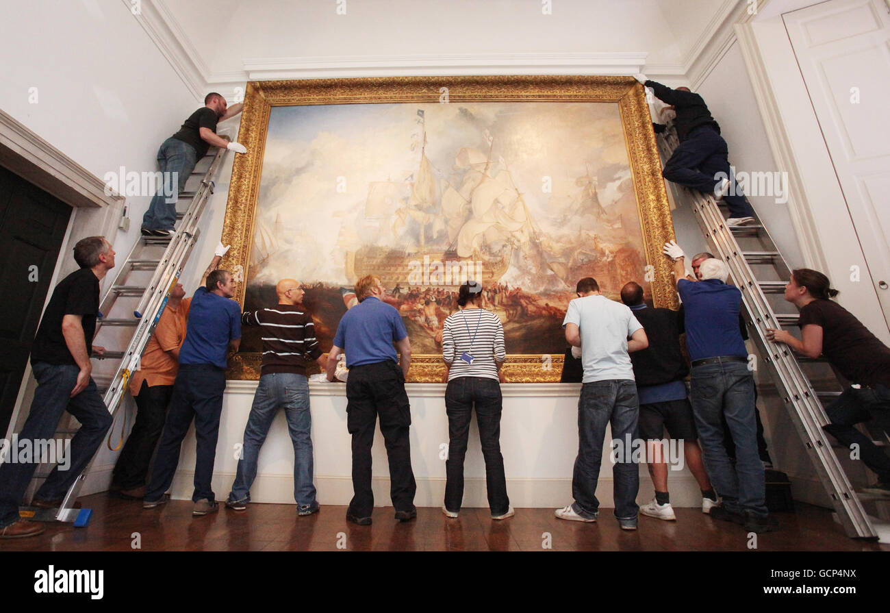J.M.W. Turner's priceless oil on canvas Battle of Trafalgar painting is re-hung by a team of experts in Queen's House at the National Maritime Museum in Greenwich after time away on a European tour. Stock Photo