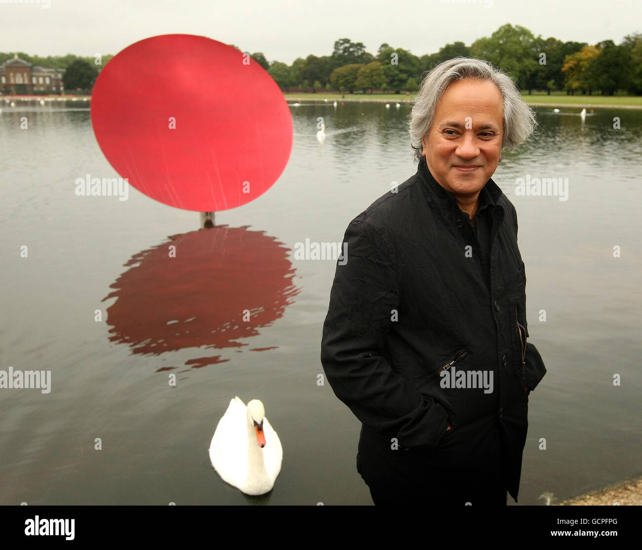 Artist Anish Kapoor is seen with 'Sky Mirror Red 2007' part of his new exhibition 'Turning the World Upside Down', which comprises four reflective stainless steel sculptures in Kensington Gardens, in central London, until March 13th 2011. Stock Photo