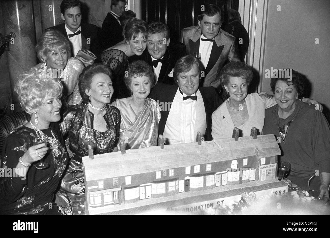 Members of the cast of ITV's soap opera Coronation Street, crowded around a cake replica of the street at the celebration to mark its 25th anniversary at the Dorchester Hotel. Front row, left to right, Julie Goodyear, Eileen Derbyshire, Thelma Barlow, William Roache, Jean Alexander and Betty Driver. Back row, left to right, Liz Dawn, Nigel Pivaro, Anne Kirkbride, Bryan Mosley and Bill Tarmey. Stock Photo