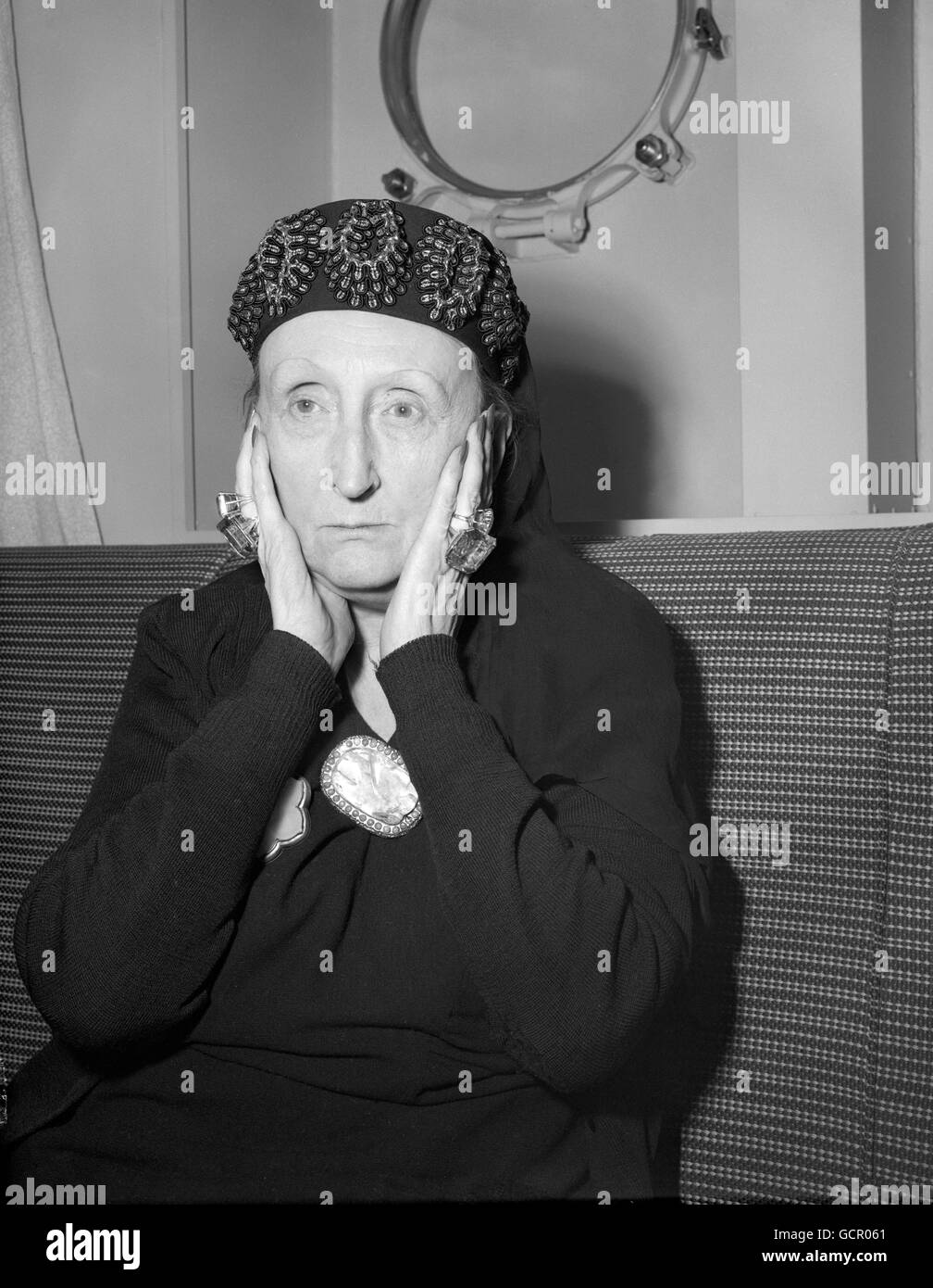 Dame Edith Sitwell - a poet, critic, lecturer and wit - cradles her face in fantastically-ringed hands as she arrives at Southampton aboard the liner United States from America, where she has been giving readings of her poetry. On a visit to Hollywood, Dame Edith met Marilyn Monroe, which brought from the film star the comment: 'I think she is one of the most wonderful women I've ever met.'. Stock Photo
