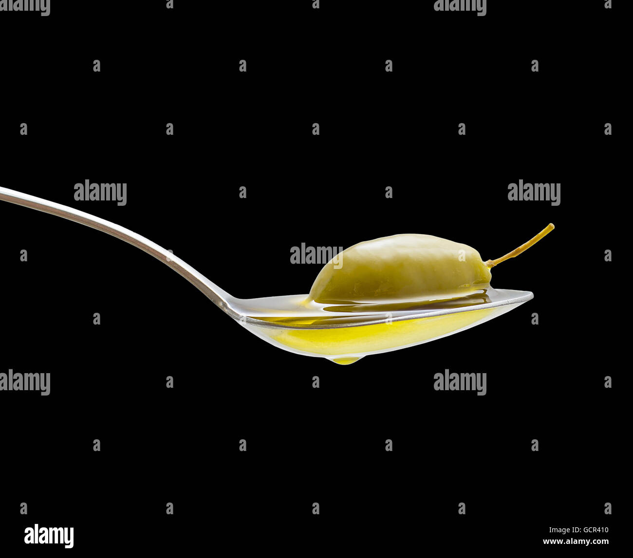Green olive in full oil spoon on black background, isolated Stock Photo