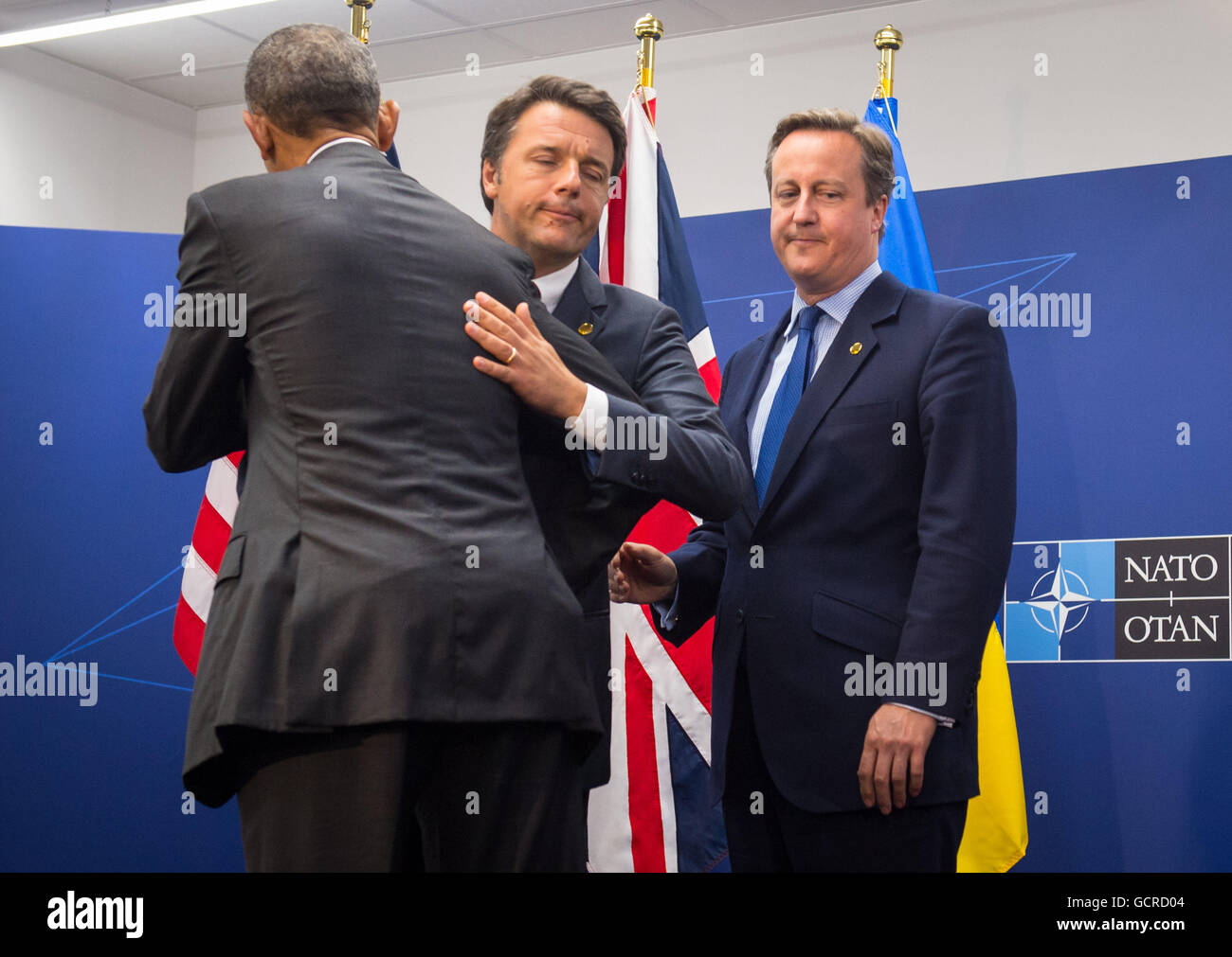 Prime Minister David Cameron (right) watches as US President Barack Obama (left) and Prime Minister of Italy Matteo Renzi hug after posing for a photograph following a meeting of the Nato Quint on day two of the Nato summit at the National Stadium in Warsaw, Poland. Stock Photo