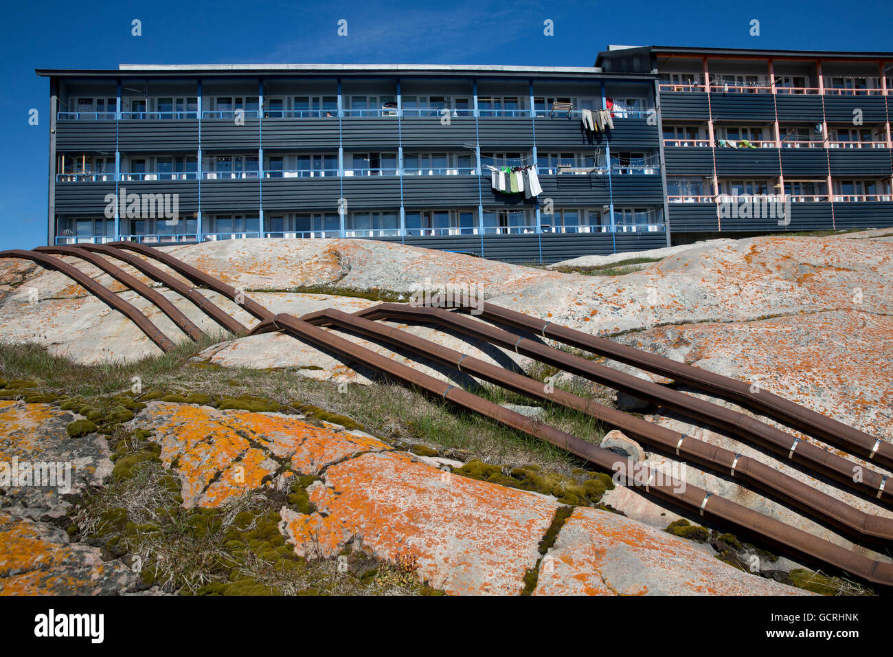 Above ground conduits and apartment buildings, Ilulissat, Greenland Stock Photo