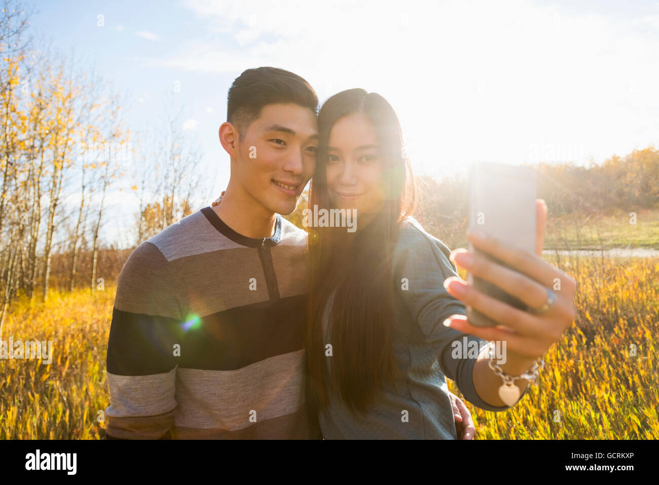 A young Asian couple enjoying time together in a park in autumn and ...