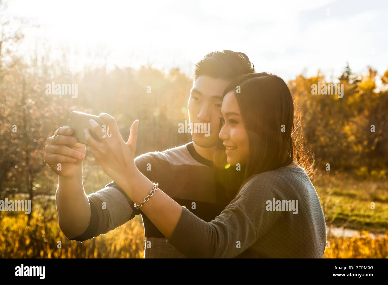 A young Asian couple enjoying time together in a park in autumn and ...
