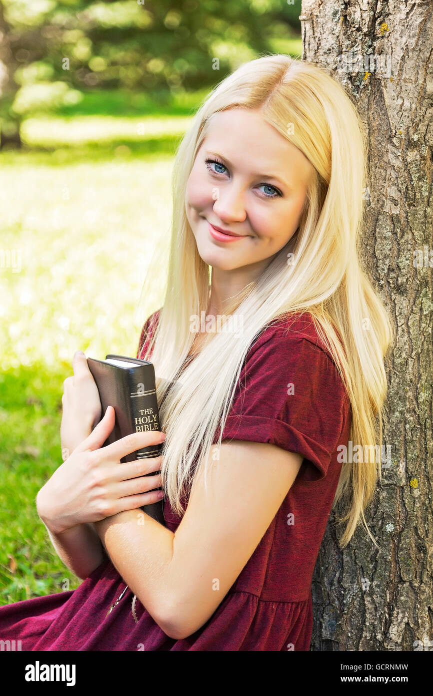 A Young Woman With Long Blond Hair Holding Her Bible Close To Her Chest While Spending Personal
