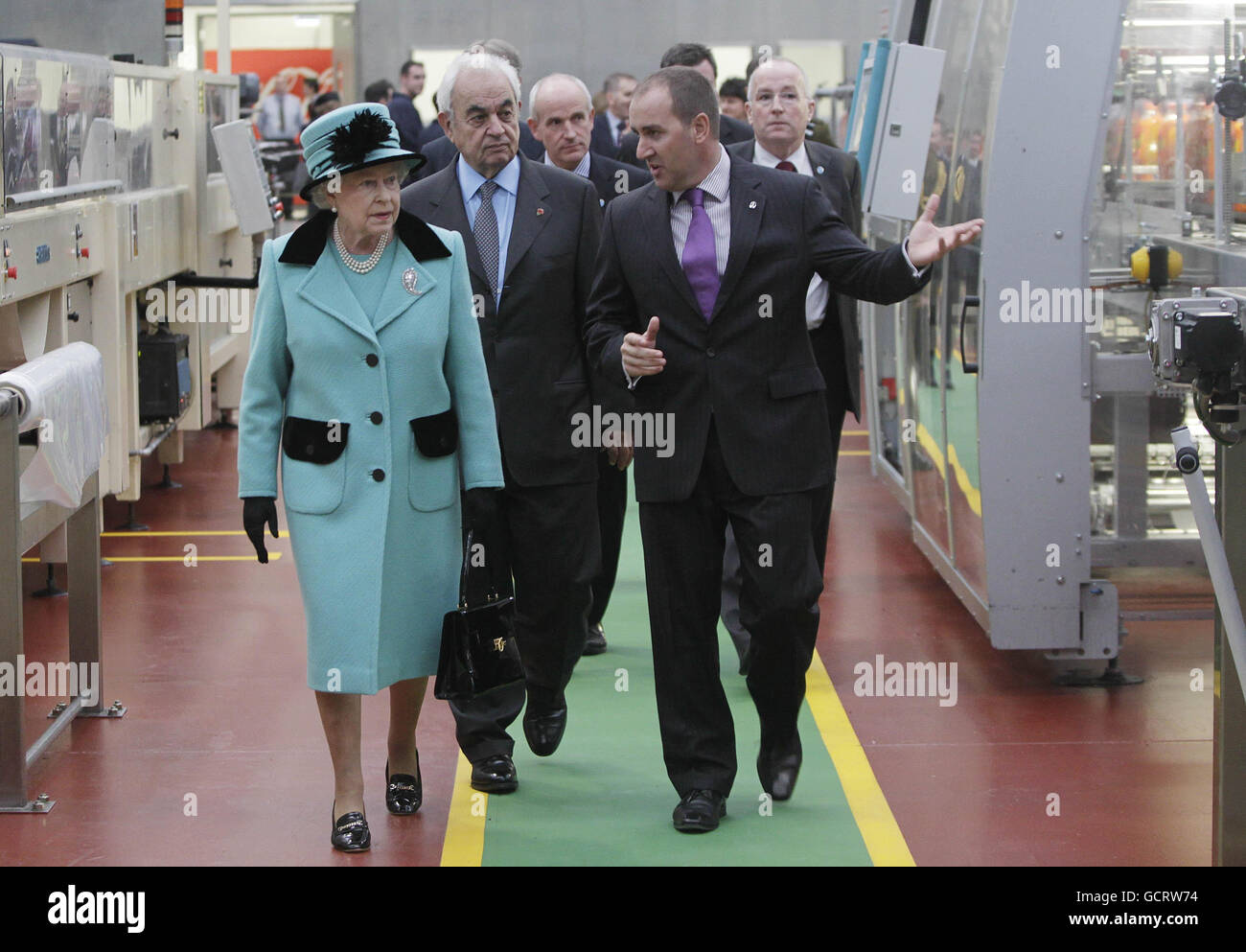 Alan Smith Regional Supply chain Director (left) and George David Chairman of Coca-Cola Hellenic (right) give Queen Elizabeth II a tour around the Coca-Cola bottling plant in Lisburn before she opened the new visitors centre. Stock Photo