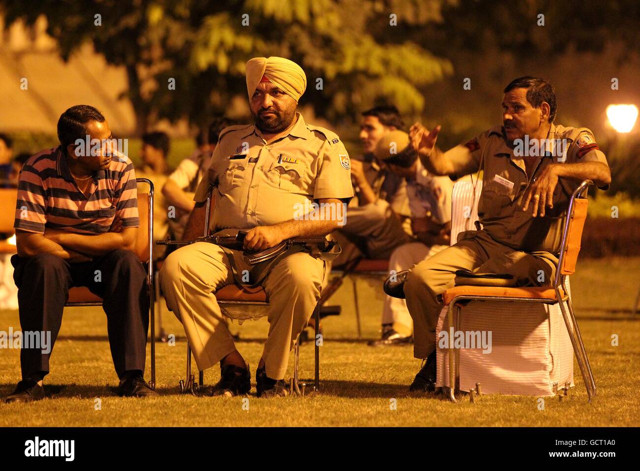 Police Officers watch the opening ceremony on a giant screen as it unfolds to officially open the 2010 Commonwealth Games at the organising committee building in central New Delhi, India Stock Photo