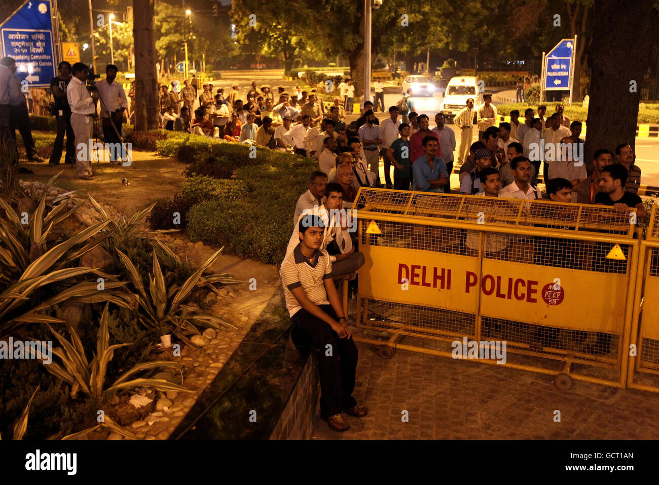 People are held behind a police barrier as they watch the 2010 Commonwealth Games opening ceremony outside the Jawaharlal Nehru Stadium in New Delhi, India. Stock Photo