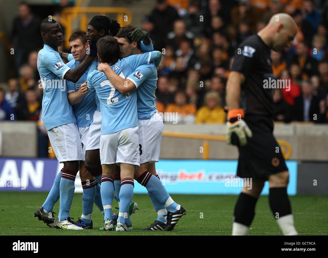 Manchester City's Emmanuel Adebayor celebrates scoring his sides first goal of the game with teammates as Wolverhampton Wanderers goalkeeper Marcus Hahnemann (right) stands dejected Stock Photo