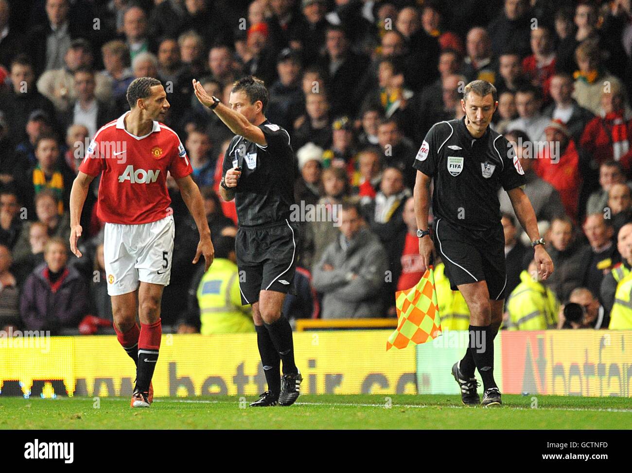 Manchester United's Rio Ferdinand (left) stares at the assistant referee (right) as match referee Mark Clattenburg (centre) signals that Manchester United's second goal, scored by Luis Nani, will stand Stock Photo