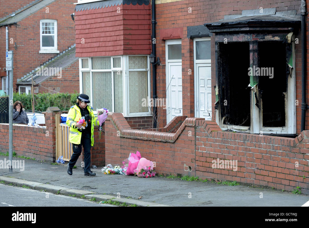 A Police officer brings flowers from the public to the scene of a house fire in Bridlington