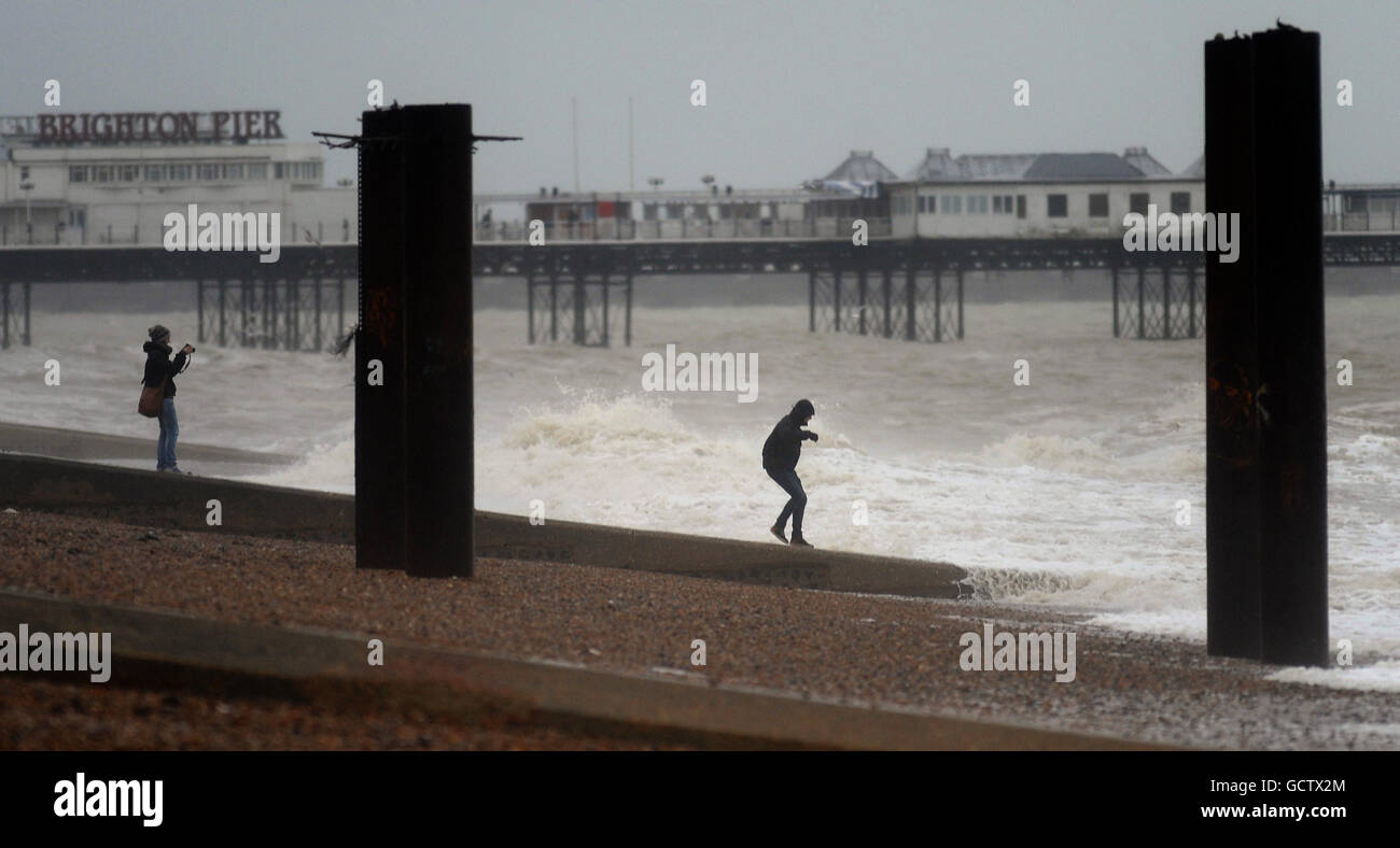 A couple play on the beach as heavy wind and rain hits the sea front at Brighton. Stock Photo