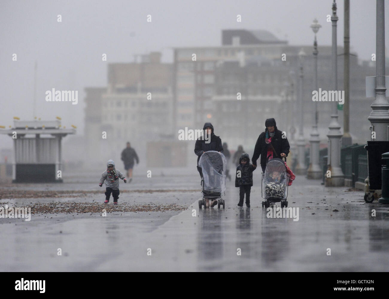 People walk along the sea front as heavy wind and rain hits Brighton. Stock Photo