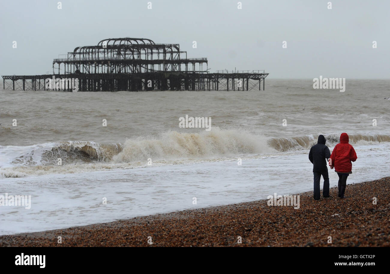 A couple walk along the beach as heavy wind and rain hits Brighton. Stock Photo