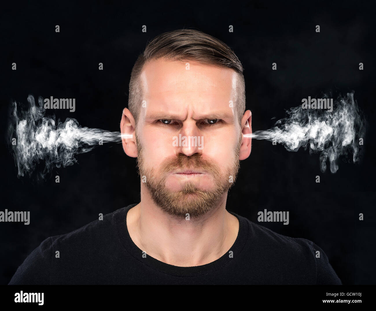 Angry man with smoke or fume coming out from his ears on dark background. Stock Photo