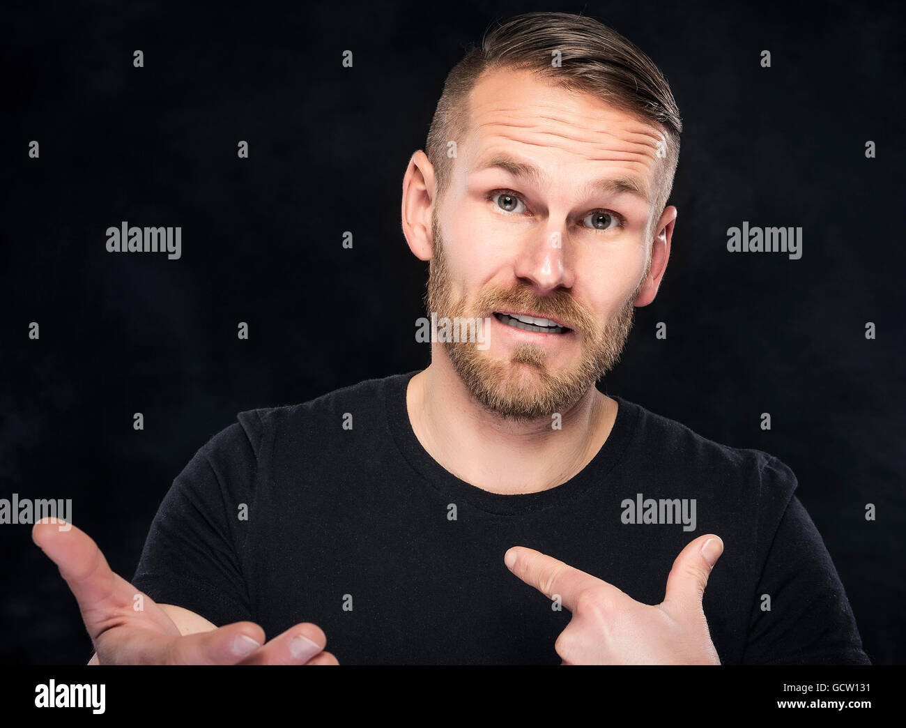 Young man in a misunderstanding on dark background Stock Photo - Alamy