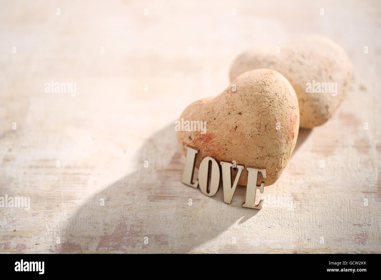 Heart of stone on the woody background with love inscription. Stock Photo