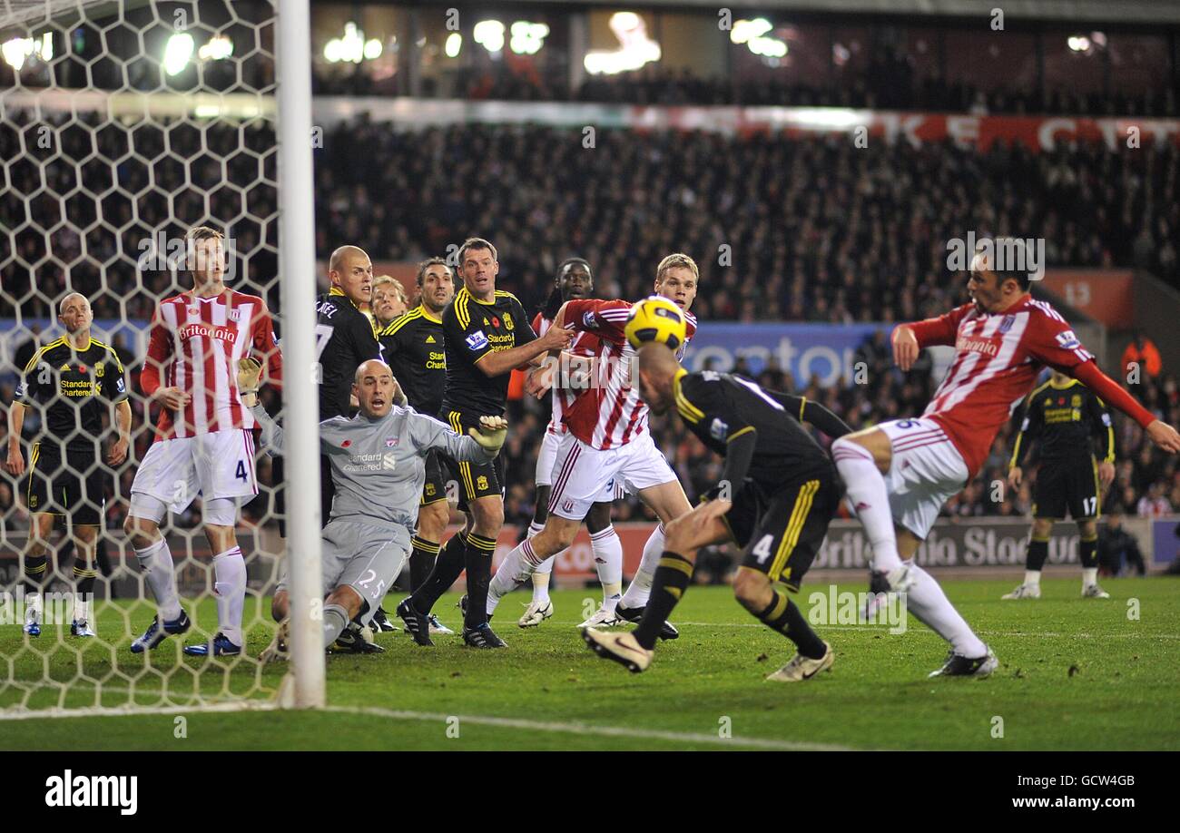 Liverpool goalkeeper Jose Reina (left) goes down as Raul Meireles (2nd right) clears the ball Stock Photo