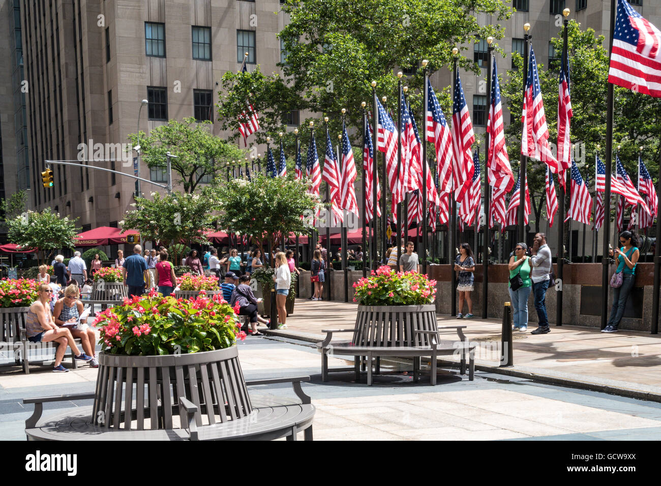 Tourists on Round benches and American Flags at Rockefeller Center ...