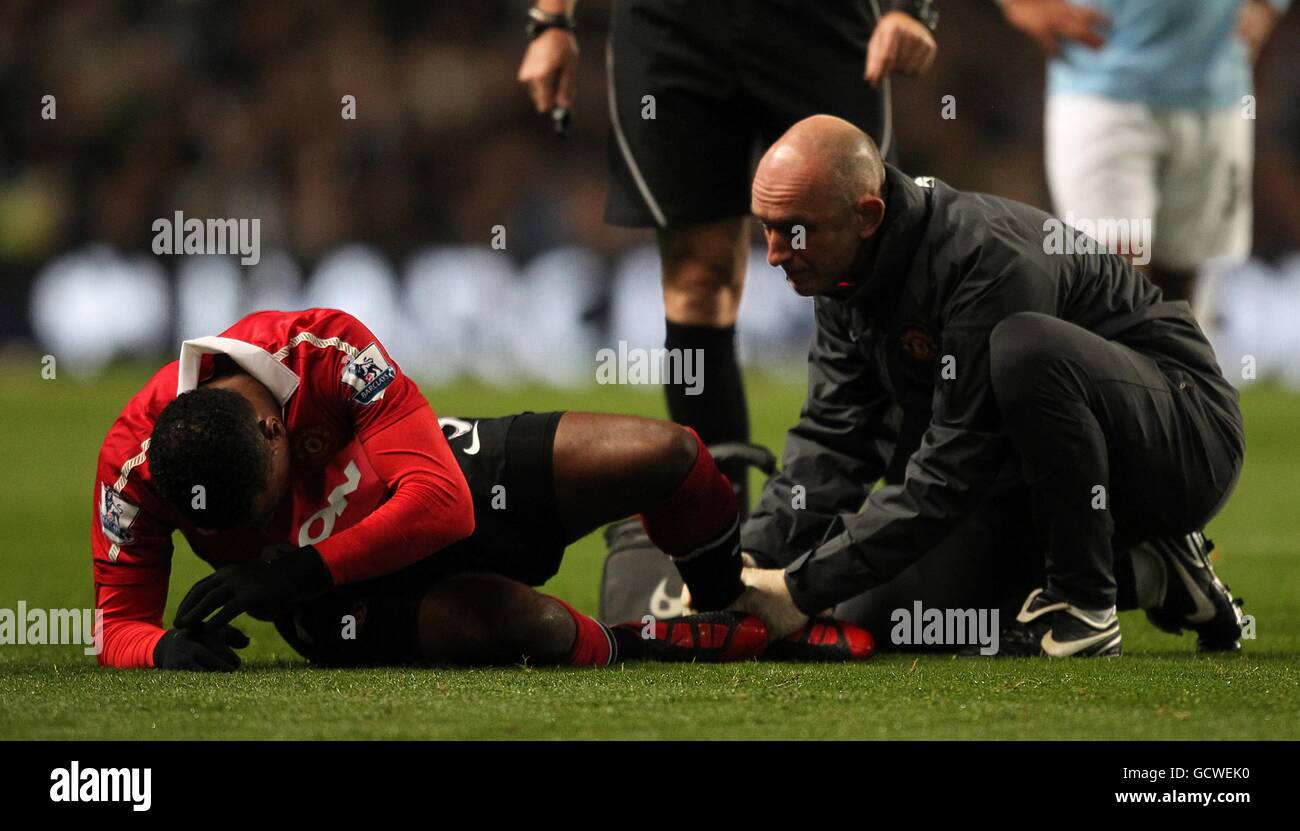 Manchester United head physiotherapist Rob Swire (right) treats Patrice Evra (left) on the pitch for a injury Stock Photo