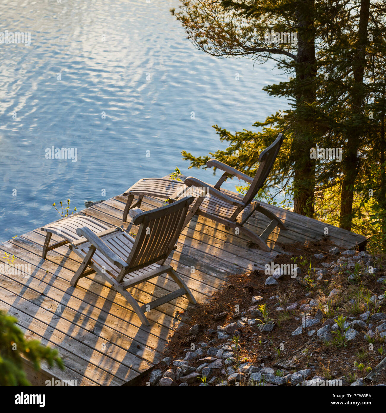 Two wooden lounge chairs on a dock looking out at Lake of the Woods at ...