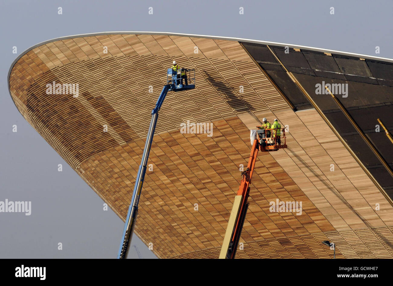 Construction workers add panelling to the velodrome at the Olympic Park in Stratford, East London. Stock Photo