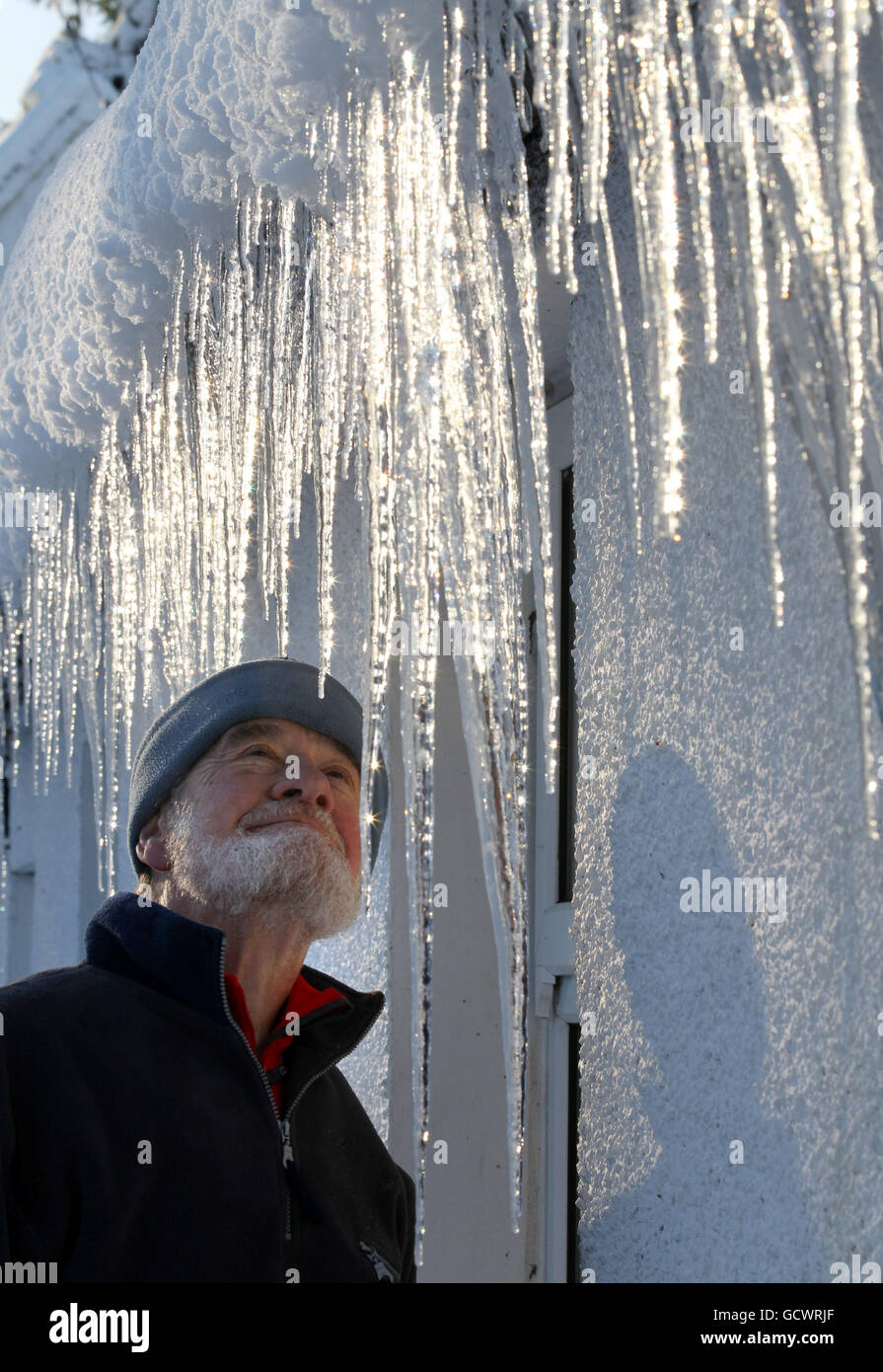 Peter Edmands looks at icicles attached to the gutter of his house in Kippen, central Scotland as the cold snap continues to hit the UK. Stock Photo