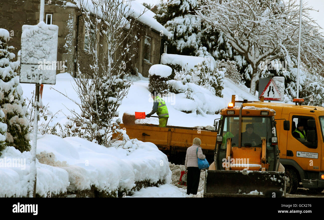 Workers scatter grit from the back of a lorry in a snow covered street in Dunblane, as heavy snow continues across the country. Stock Photo