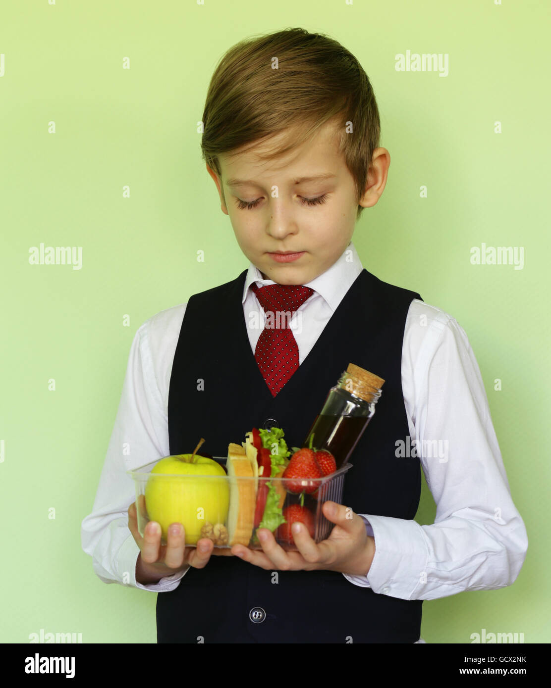 Boy in school uniform and lunch box with sandwich and fruits healthy