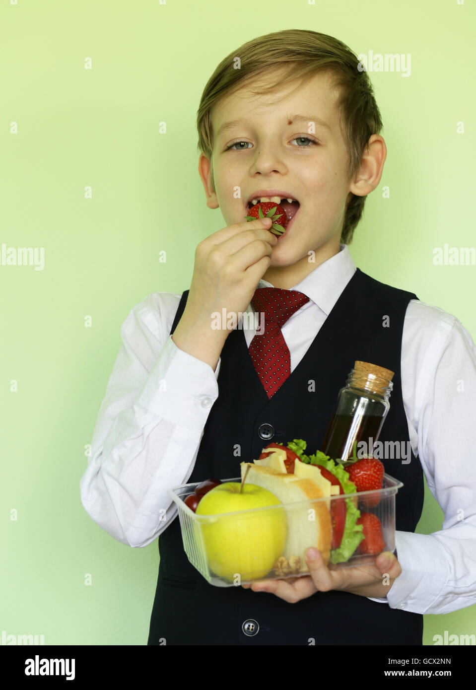 Boy in school uniform and lunch box with sandwich and fruits healthy