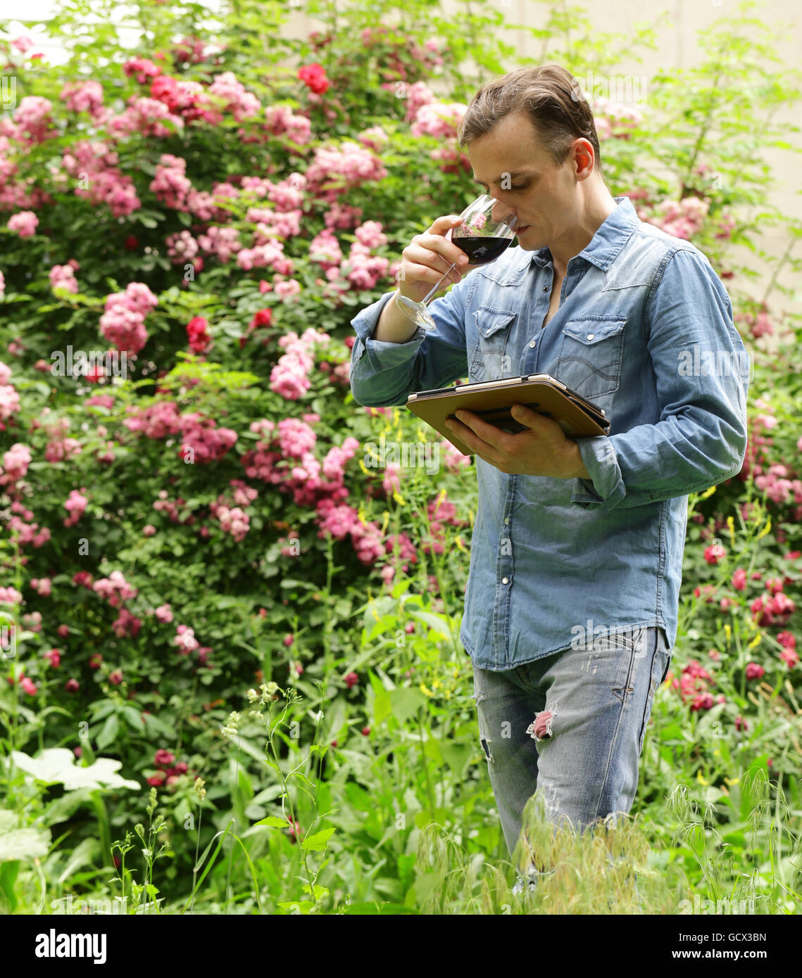 Young man tasting red wine, outside in the garden Stock Photo Alamy