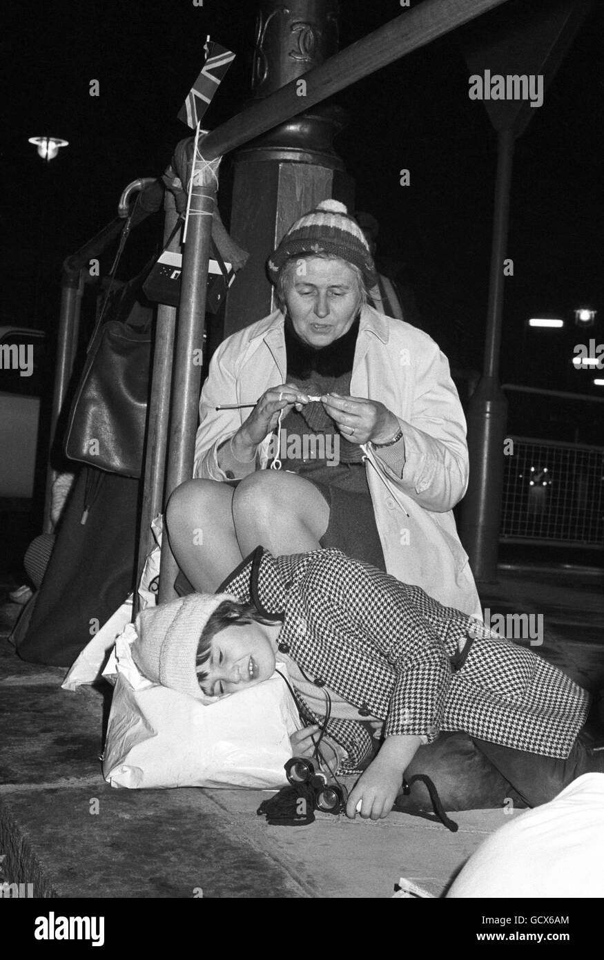 A woman knits and six year old April Gardiner, of Orpington, Kent, sleeps, as they wait outside Westminster Abbey for the wedding of Princess Anne to Captain Mark Phillips. Stock Photo