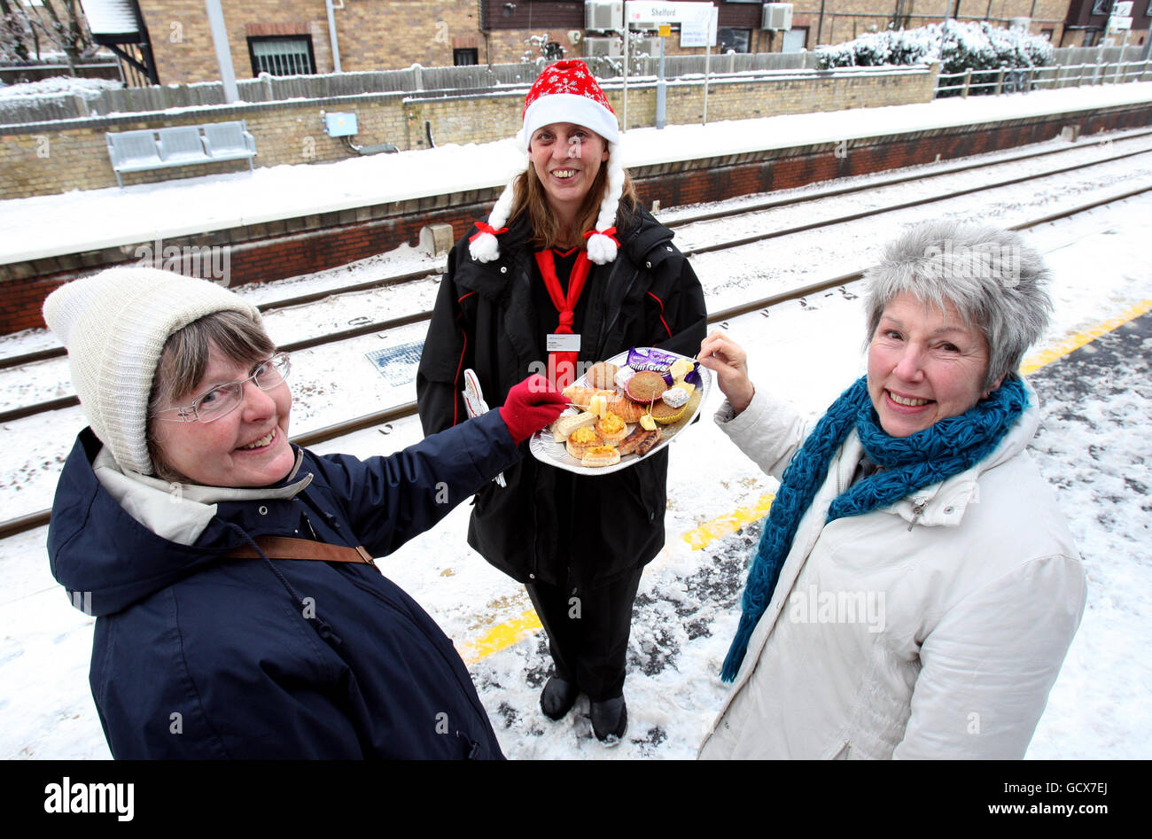 Booking Clerk, Angela Milton, offers passengers Christine Pammenter (left) and Veronica Stower a festive snack on the platform of Shelford Village Railway Station in Cambridgeshire. Stock Photo