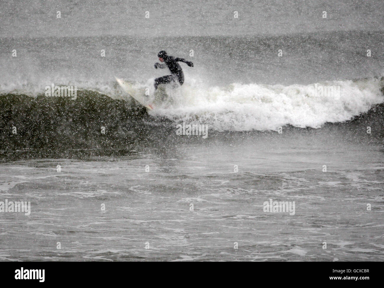 A surfer braves the freezing weather conditions in pursuit of his sport at Aberdeen beach, Scotland, as more snowfalls are forecast for much of the UK. Stock Photo