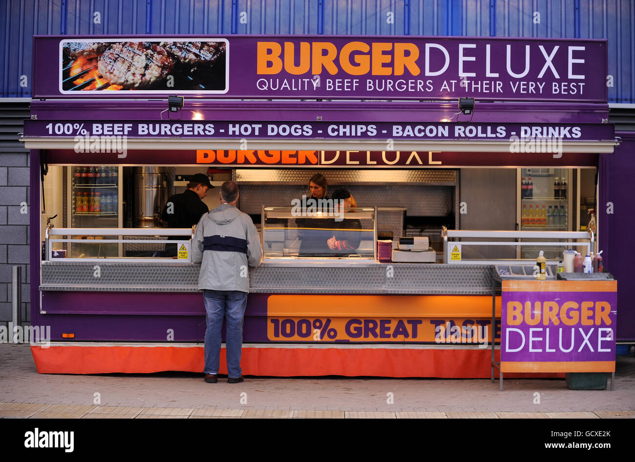 Fans make their way past a Burger Deluxe catering van outside of the Cardiff City Stadium Stock Photo