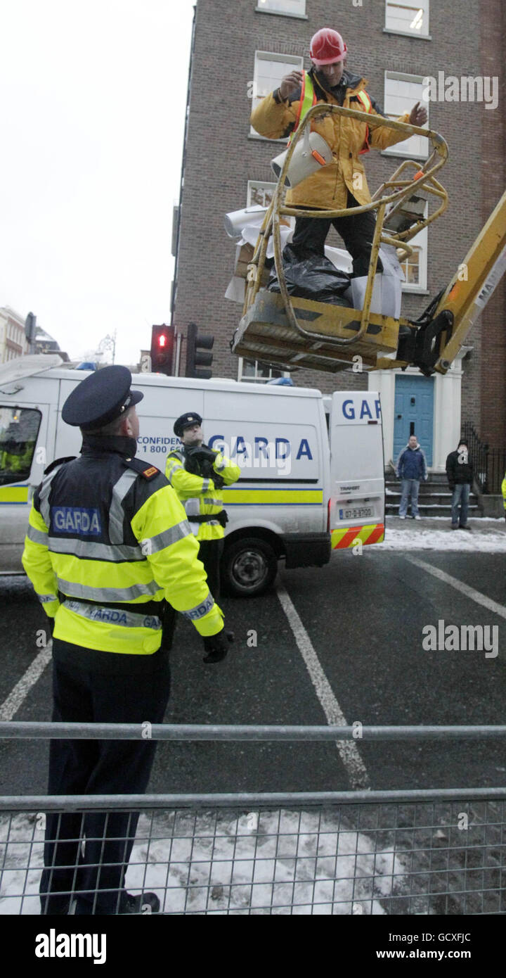 A man in a cherry picker covered with a number of slogans attacking politicians and the banking sector to protest outside the gates of Leinster House, Dublin, converses with gardai on Budget day. Stock Photo