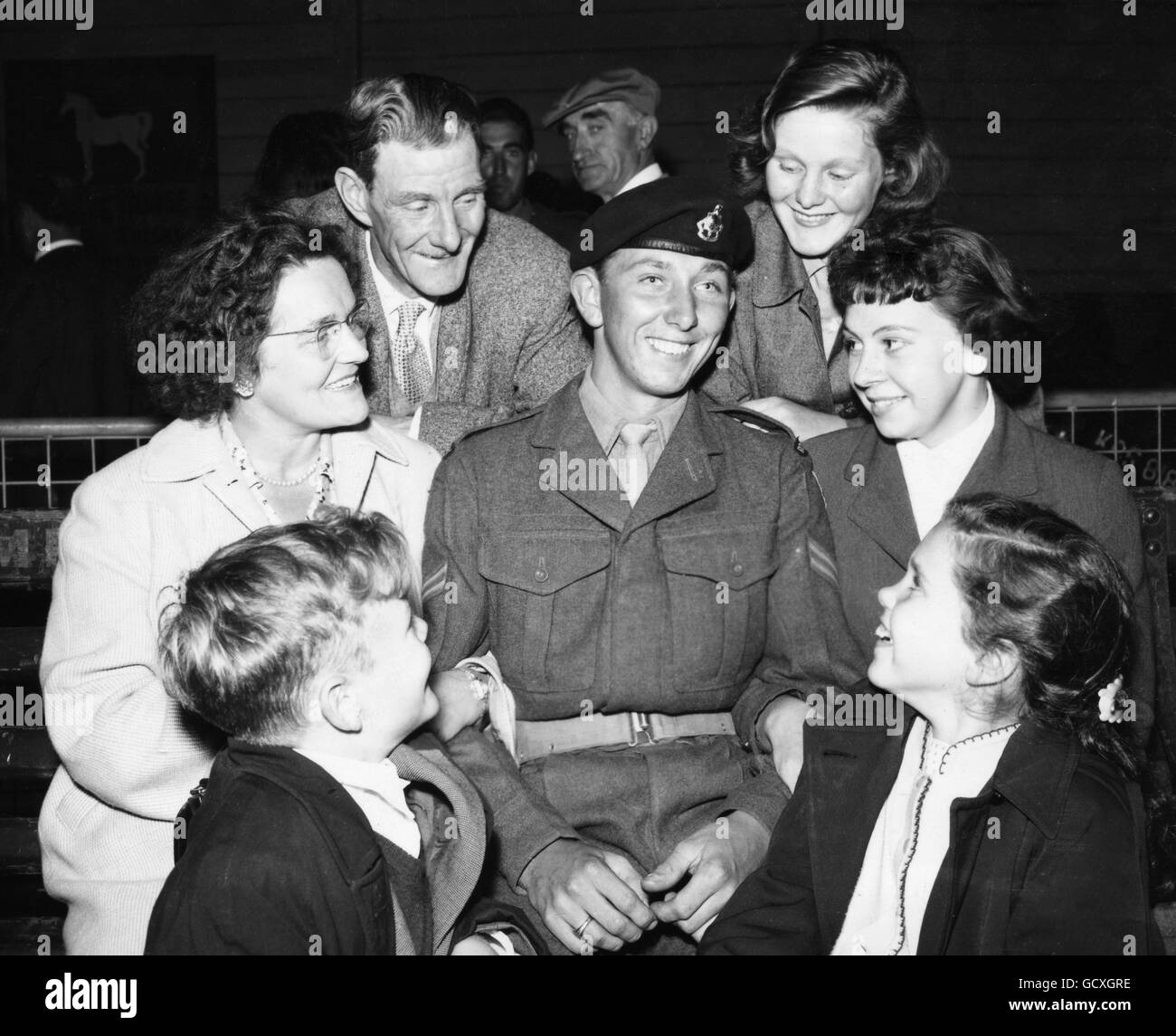 Centre of a family circle at Southampton is Corporal David Menzies, Royal Sussex Regiment, of Brighton, who arrived home in the Troopship Asturias after serving overseas for 14 months with his battalion of the Royal Sussex, the last British battalion to leave Korea. Greeting him are his mother (on left), his father, his sisters Irene 14 and Wendy 11, his brother John, aged 9, and (holding his arm on right) his girlfriend, Sybil Rogers. David and Sybil are about to become engaged. Stock Photo