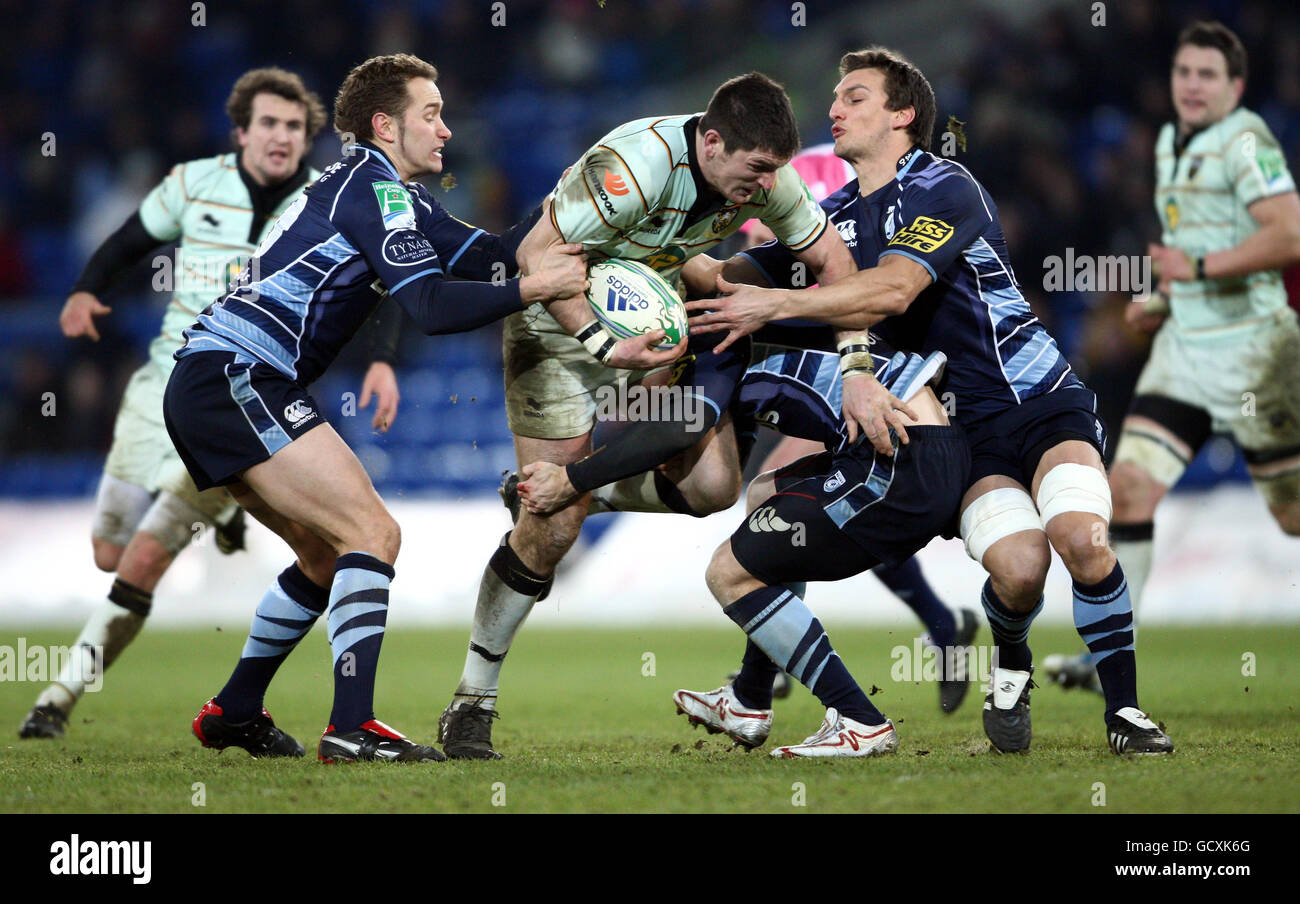 Northampton Saints Phil Dowson is tackled by Cardiff Blues Dan Parks and Sam Warburtond during the Heineken Cup match at the Cardiff City Stadium, Cardiff. Stock Photo