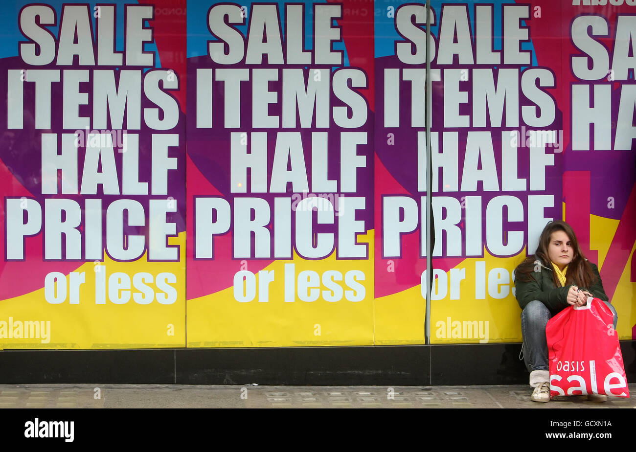 A shopper sits on the floor near sale signs on Oxford Street, in central London. PRESS ASSOCIATION Photo. Picture date: Monday December 27, 2010. Crowds of shoppers lined the high street before first light as major stores and retailers were expecting a bumper day in the Christmas sales. Queues formed outside Harrods and on Oxford Street in central London as early as 6am for the bank holiday clearances. Department stores John Lewis and Harrods opened their doors for the first time since Christmas after staying closed on Boxing Day, and were expecting a massive boost in trade. See PA story Stock Photo