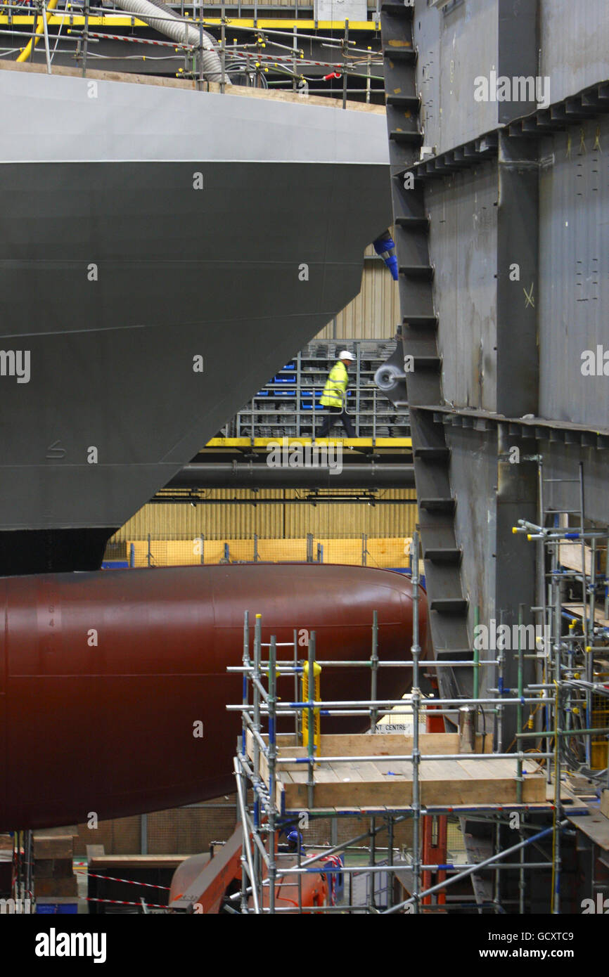 Ship builders walks past a hull section of the first of two Queen