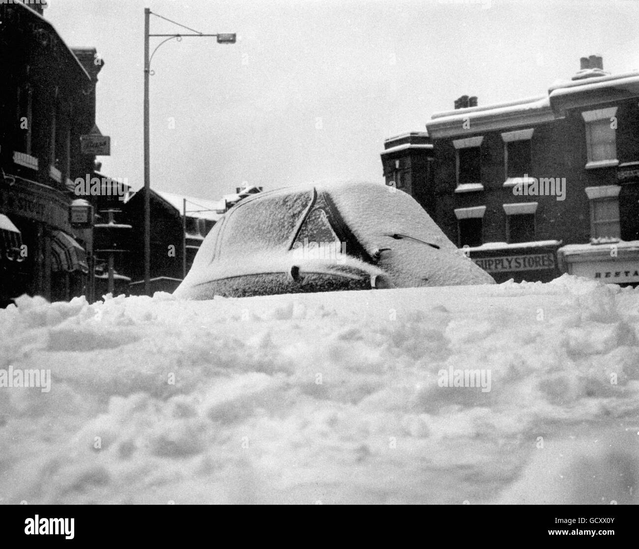Following an all night fall, snow has drifted and almost covered a bubble car at Herne Hill, South London. Stock Photo