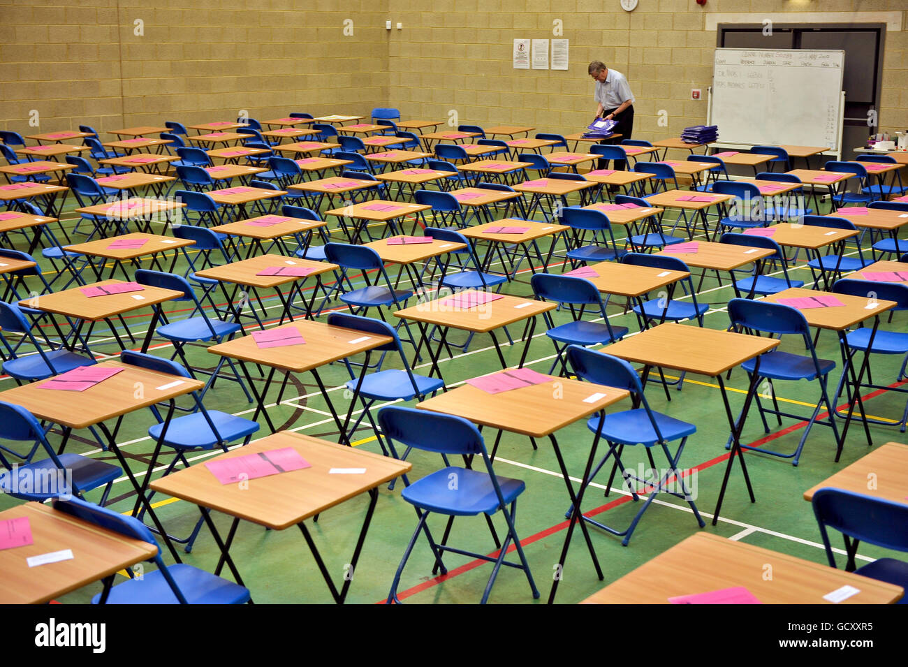 An exam invigilator prepares an A-level maths exam inside a sports hall Stock Photo