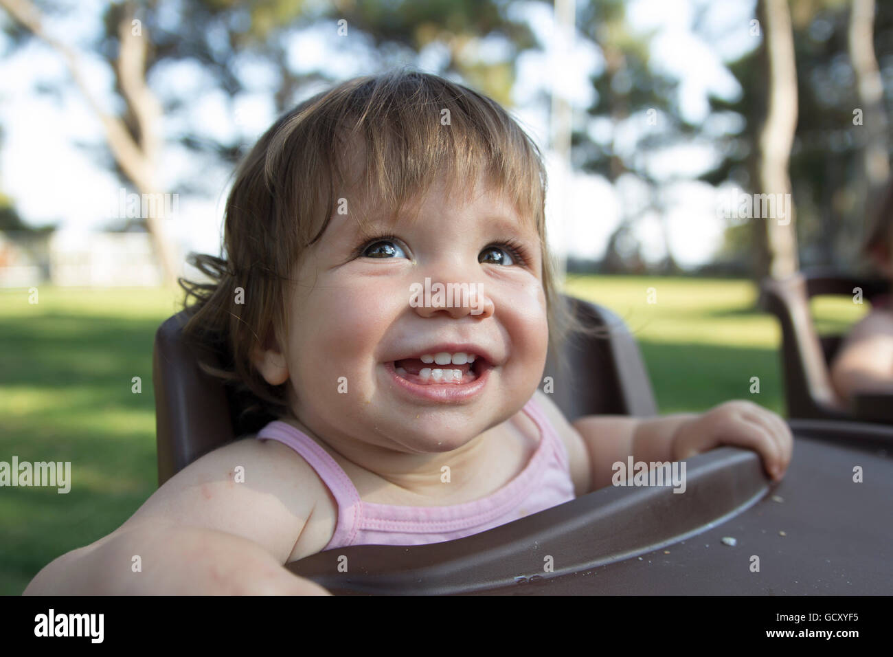 happy baby enjoying in park waiting in feeding chair for food Stock Photo