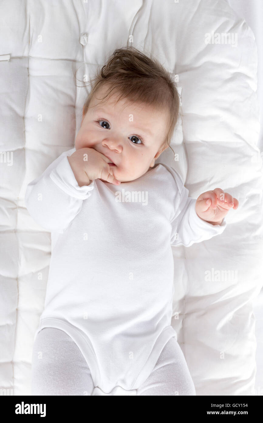 teething baby with hand in mouth Stock Photo