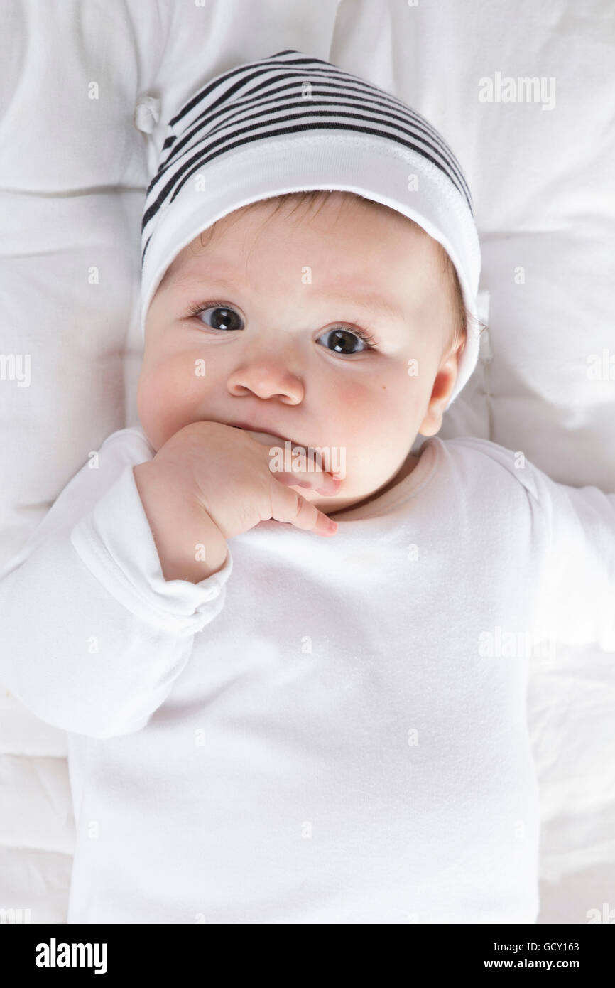 teething baby wearing a hat with hand in mouth close-up Stock Photo