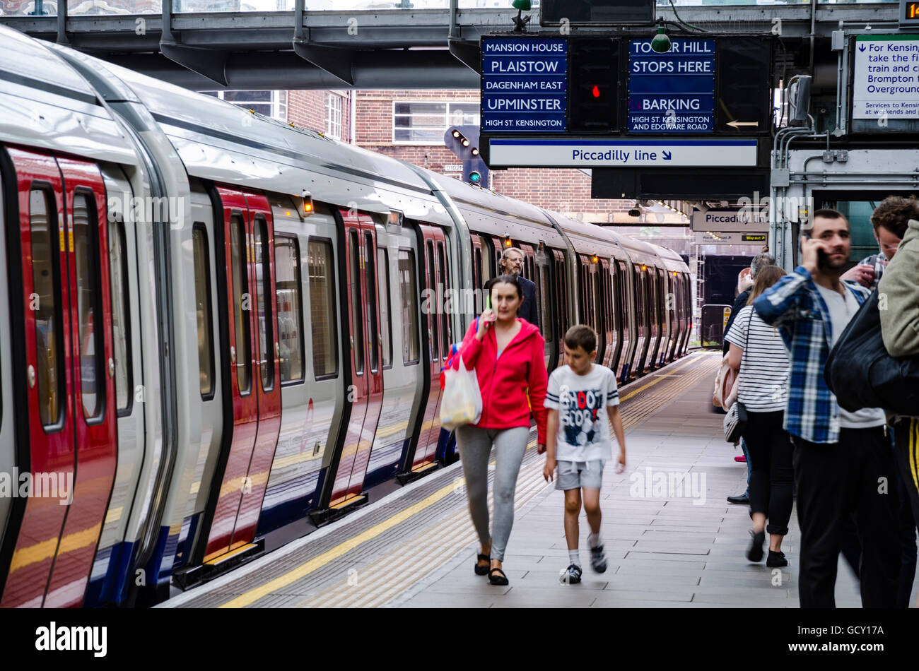 A train sits in Earl's Court London Underground Station waiting to depart as a mother and child hurry along the platform. Stock Photo