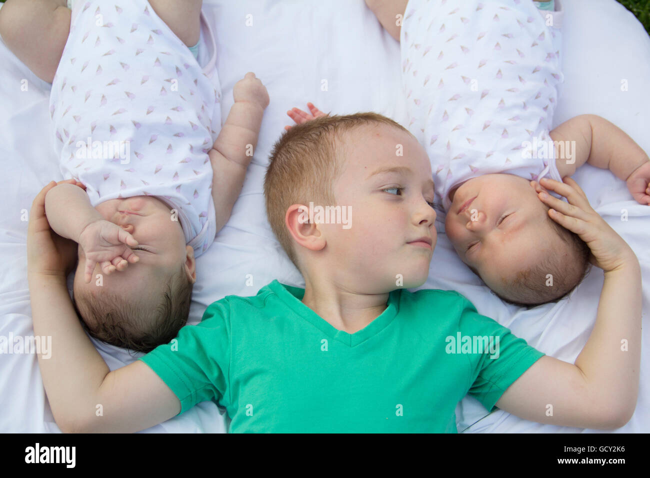 caring brother holding his twin sisters with love close-up Stock Photo