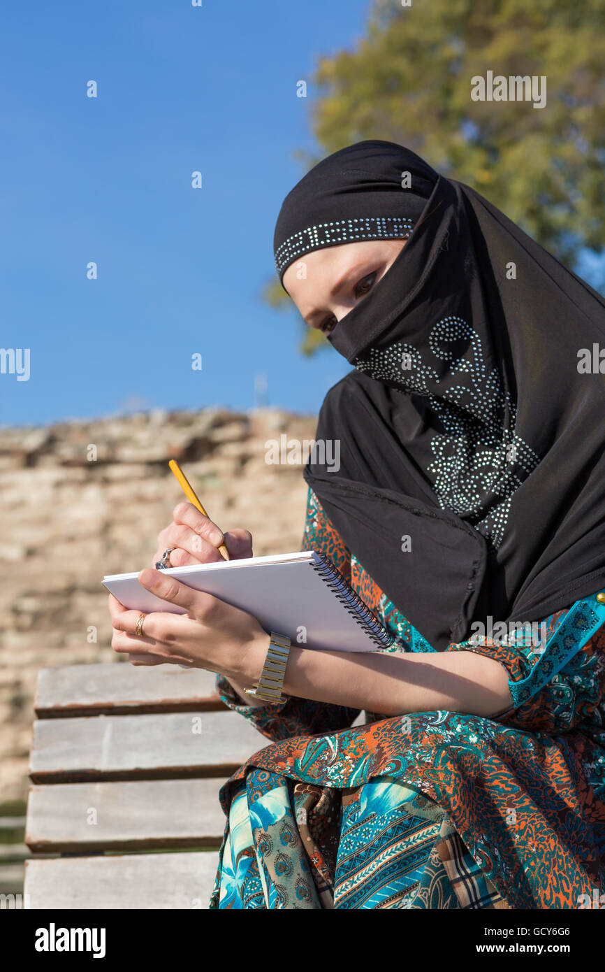 Arabic Woman drawing Sketch in Paper Notepad with Pencil Stock Photo