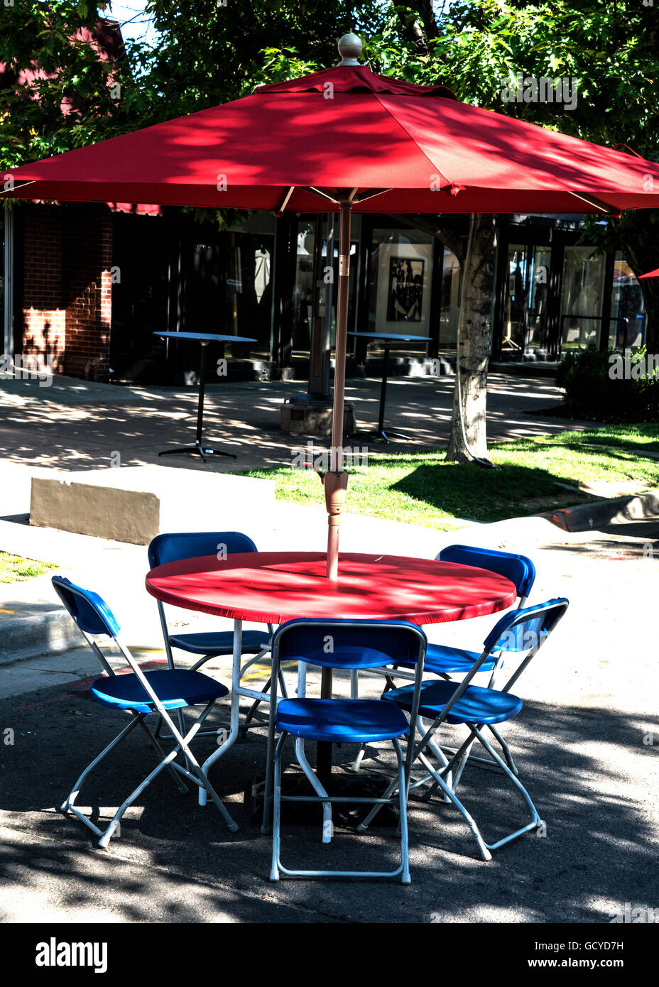 Red umbrella and red table with blue chairs at Cherry Creek Art Festival in Denver Colorado Stock Photo